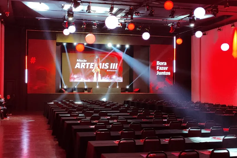 Auditório Munique durante evento, com palco iluminado e plateia cheia