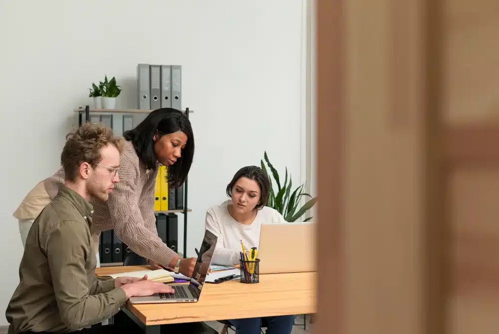 Equipe de três colaboradores reunida em um espaço de trabalho