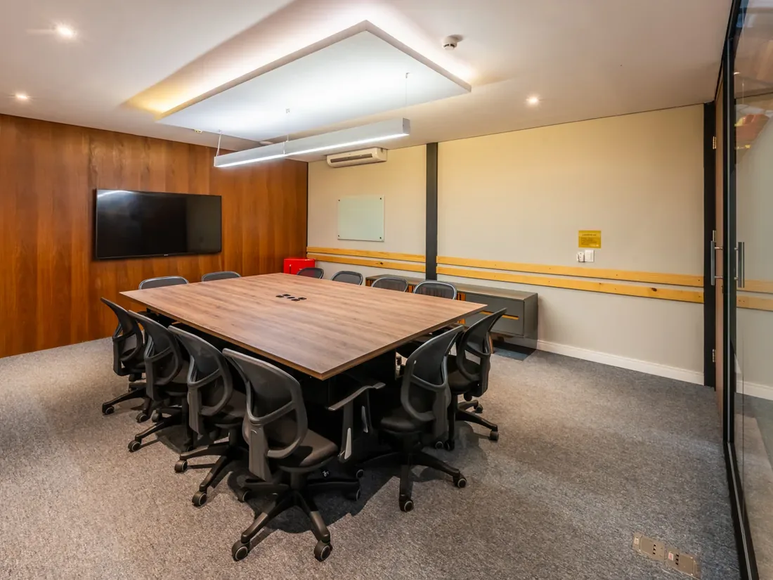 Sala Celebração da unidade COW Berrini vista de outro ângulo, com mesa para 12 pessoas e TV